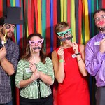 Four people holding fake glasses and fake mustaches to their face